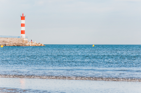 Lighthouse of Port-La-Nouvelle in red and white on cloudy sky in Occitanie, Franceの写真素材