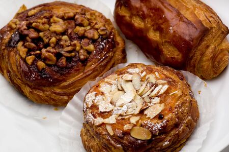 Pain au chocolat, cinnamon walnut, and apricot almond pastries on white plate.の写真素材