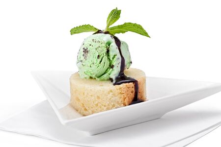 A scoop of mint ice cream on a slice of pound cake with chocolate sauce and garnished with mint.の写真素材