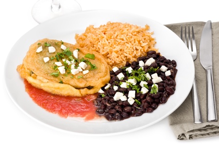Cheese chile relleno with black beans and rice garnished with cilantro on white plate.の写真素材