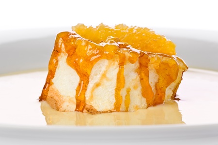 Floating Island Dessert: Meringue topped with caramel and a fresh slice of orange floating on vanilla custard on a white plateの写真素材