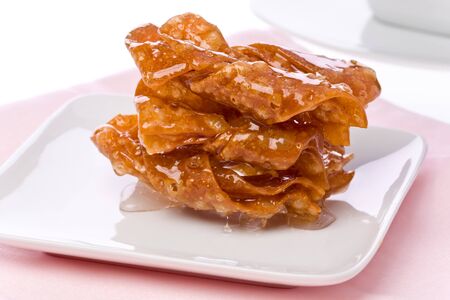 Three sticky butterfly cookies on a small plate on a pink napkin.