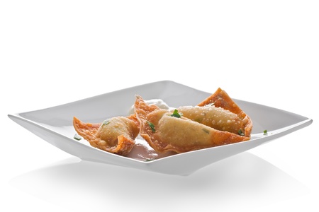 Appetizer plate with three pieces of crab rangoon and a mustard sauce against a white background.の写真素材