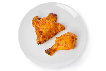 Two pieces of tandoori chicken on a white plate against a white background の写真素材