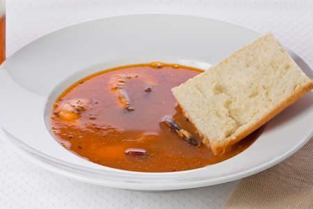Bowl of spicy shrimp soup in a white bowl with a piece of bread on the side.の写真素材