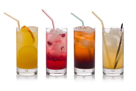 Four glasses of cold, fresh, homemade sodas with ice and drinking straws against a white background. Flavors include orange, raspberry, cola and vanilla ginger.の写真素材