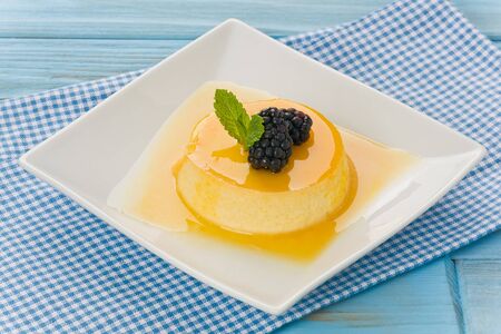 Passion fruit flan with blackberries and mint on white plate.の写真素材