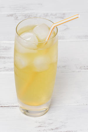 Glass of iced green tea with a straw, on a white, painted wood background.の写真素材