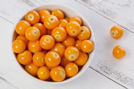 A small bowl of Cape Gooseberries, or goldenberries, on a painted white background.の写真素材