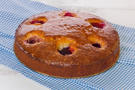 Almond Plum Cake on a blue checkered cloth on painted white background.の写真素材