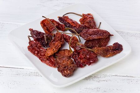 A small plate of dried Ghost chile peppers on a painted white background.の写真素材
