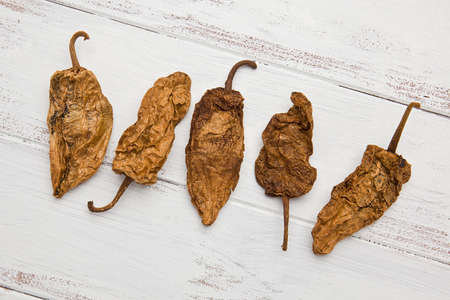 Five Chipotle chile peppers on a white painted background.の写真素材
