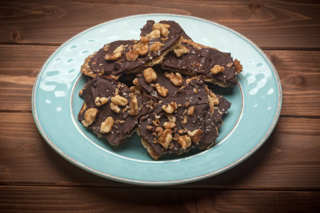Several pieces of homemade chocolate, toffeee, matzo crack on a plate on a wooden background.の写真素材