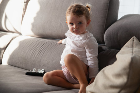Portrait of a baby girl on the sofa at home attentive to the scene