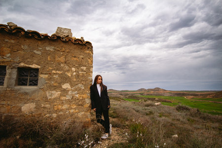 Beautiful young woman resting on the wall of an old hut in the desert