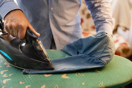Close up of an older man's hands ironing clothes at homeの写真素材