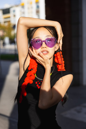 Portrait of young asian girl looking at camera with hands framing her face in the streetの写真素材