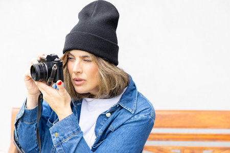An engaged photographer with a vintage camera focuses intently on his subject, dressed in urban...