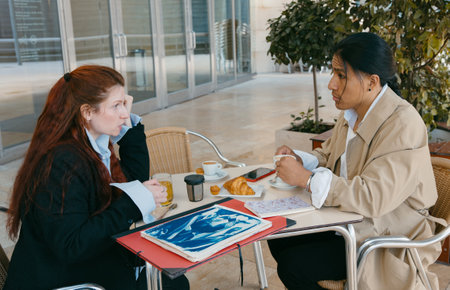 Two professionals engage in a serious business discussion over a morning coffee at an outdoor cafe setting.の写真素材