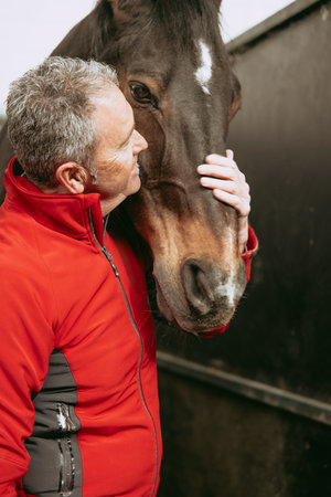 Man enjoying the bonding he has with horse the he cares for and ridesの写真素材