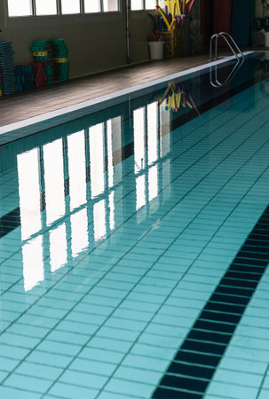Detailed view of a lane in an indoor swimming pool with clear, transparent water reflecting the...