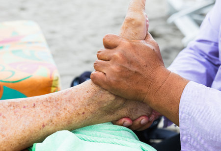 Hands providing therapeutic foot massage to an elderly womanの写真素材