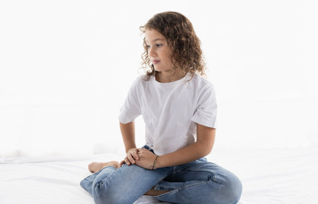 Portrait of a girl sitting calmly, looking away in a relaxed studio setting, copy space.の写真素材