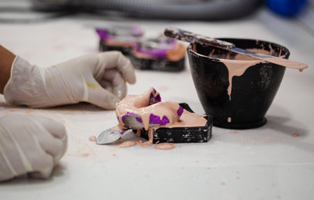A person prepares a dental mold with a purple-colored paste in the laboratoryの写真素材