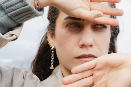 Close-up of a young woman using her hands to shield her face outdoors.の写真素材