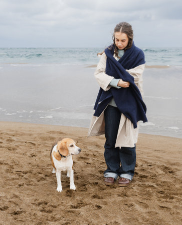 Young woman bundled up with her dog on a coastal walkの写真素材