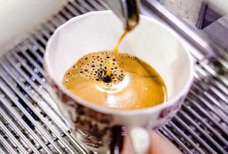 Detailed shot of espresso flowing into a ceramic cup with rich coffee cremaの写真素材