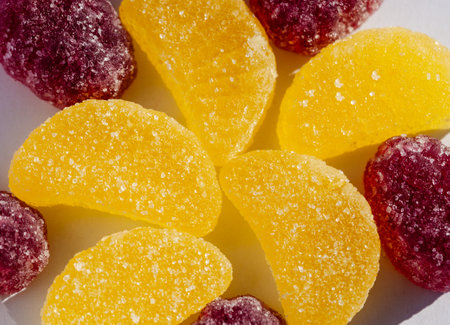 Detailed view of yellow and purple gummy candies with sugar texture on a white surface.