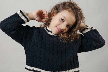 Playful 9-year-old girl posing with a charming smile in the studioの写真素材