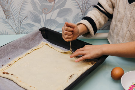 Detailed view of a child's hands sealing puff pastry filled with chocolate.