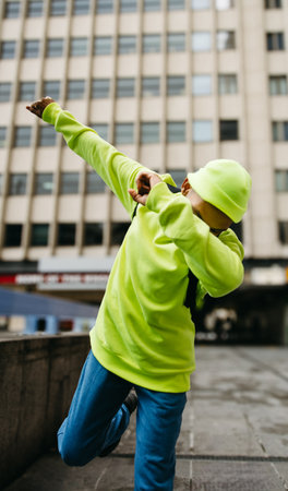 Person in bright clothing striking dance pose on city streetの写真素材