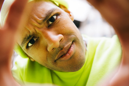 Man peeking through hands with curious expression in urban background