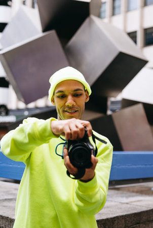 Young multiracial man shooting with camera outdoors in urban area