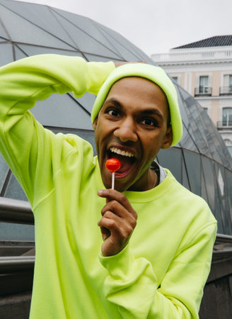 Close-up of joyful young man holding red lollipop in the cityの写真素材