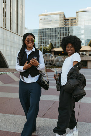 Two stylish Black friends smiling and looking at the camera in the city