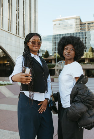 Two young Black women taking a selfie in an urban area with tall buildingsの写真素材