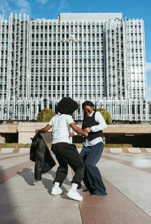 Two African women dancing and having fun outdoors in an urban plaza
