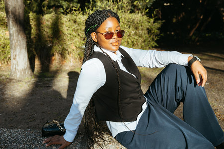 Stylish teenage girl with braids enjoying the sun in a parkの写真素材