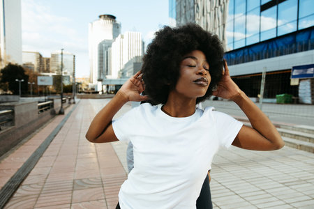 Afro woman with closed eyes dancing in city environment
