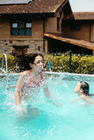 Two girls enjoying summer splashing water in the garden poolの写真素材