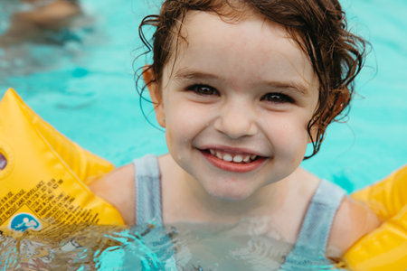 Portrait of a happy three-year-old girl in the pool with floatiesの写真素材
