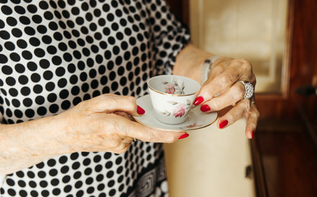 Close-up of senior woman is hands holding a vintage porcelain teacupの写真素材