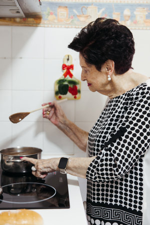 Senior woman cooking hot chocolate at home in the kitchenの写真素材