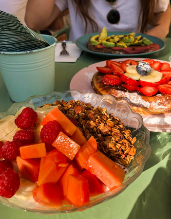 Colorful brunch with fresh fruit, granola and waffles served al fresco