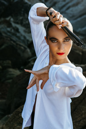 Teenage girl dancing by the ocean with a black fanの写真素材