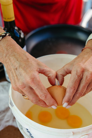 Woman cracking eggs into a bowl to prepare omelette
